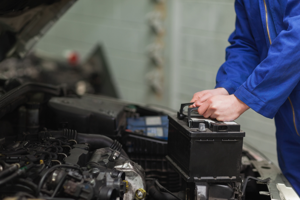 image of mechanic installing new battery into a vehicle